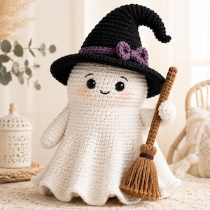 May include: A white crocheted ghost doll wearing a black witch hat with a purple band and bow. The ghost has black safety eyes, a small stitched smile, and pink cheeks. It holds a brown crocheted broomstick with a textured handle and bristles.