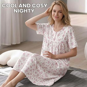 May include: A white nightgown with a pink floral pattern, short sleeves, a round neckline, and a button-down front placket. The text COOL AND COSY NIGHTY is printed in the upper left corner. The garment features a gathered bodice and lace trim.