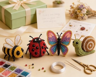 Puede incluir: Una colección de figuras de insectos con cuentas, que incluyen una abeja, una mariquita, una mariposa y un caracol. La abeja es amarilla y negra, la mariquita es roja con puntos negros y la mariposa tiene alas rosas, azules y moradas. También hay una caja de regalo verde y materiales de manualidades.
