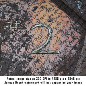 May include: A close-up of a weathered, orange-brown surface with a gold-colored number "2" painted on it. The surface is covered in a pattern of faded, overlapping text that reads "Junque Drunk".