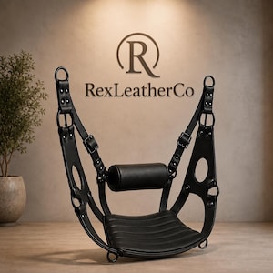 May include: A black leather sling seat featuring a horizontal cylindrical headrest, adjustable buckled straps, and metal ring hardware. The structure includes side cutouts and a ribbed seat base. The text RexLeatherCo is visible in the background.