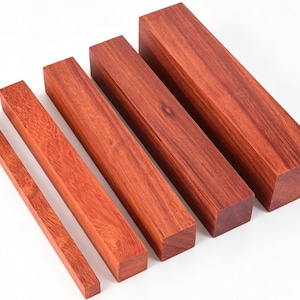 May include: Several rectangular blocks of reddish-brown wood, varying in size, are arranged diagonally. The wood grain is clearly visible. These blocks are likely intended for woodworking or craft projects, with the different sizes offering versatility.