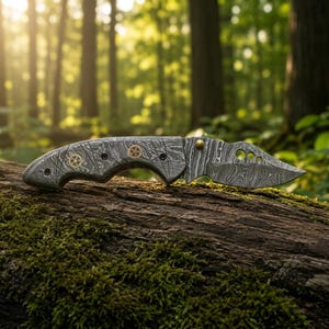 May include: A folding pocket knife featuring a distinct gray and black wavy Damascus steel pattern on both the handle and the blade. The handle includes two circular brass inlays with intricate gear-like designs and a single brass thumb stud.