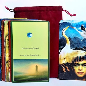 Può includere: Un mazzo di carte oracolo con un sacchetto con coulisse bordeaux. Le carte presentano illustrazioni colorate, tra cui un volto di donna, uccelli e una giraffa. Una carta riporta il testo "Daimonion-Orakel" e "Schau in den Spiegel und ...".