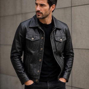 Könnte beinhalten: Schwarze Lederjacke mit Knopfleiste, zwei Brusttaschen und Kragen. Die Jacke wird mit einem schwarzen T-Shirt und einer schwarzen Jeans getragen. Das Model hat die Hände in den Taschen.