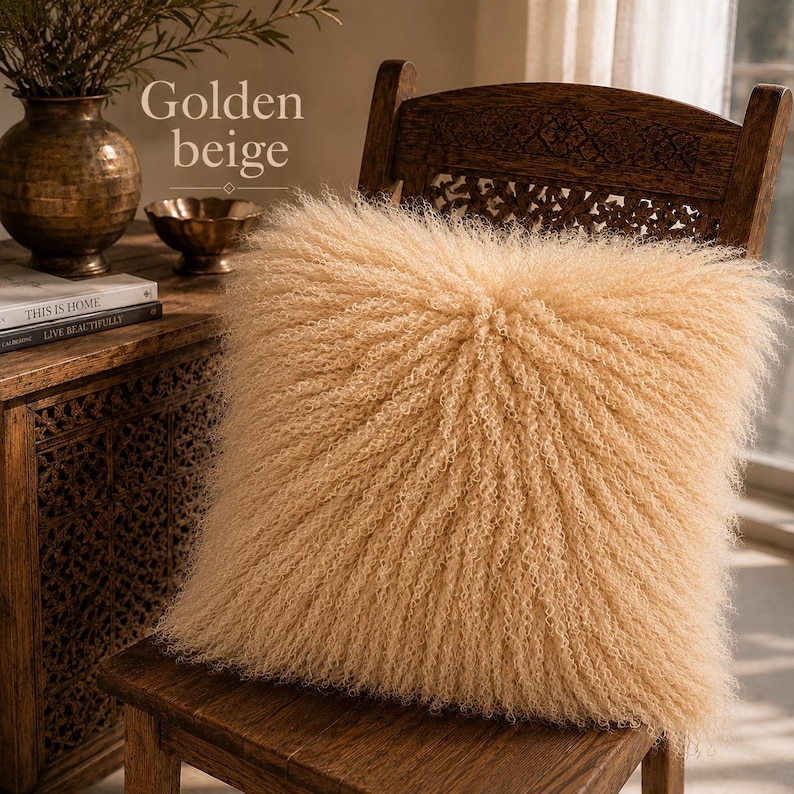 May include: A square throw pillow in a golden beige color, featuring a long, curly, shaggy texture across its entire surface. The pillow is positioned on a wooden chair, with the text Golden beige visible in the upper left corner of the image.