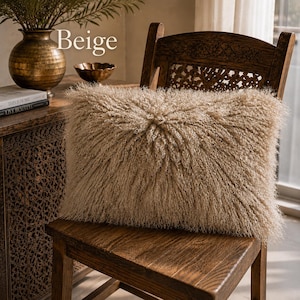 May include: A rectangular beige pillow with a long, shaggy, textured pile surface. The pillow features a central radiating pattern where the fibers extend outward from the middle. The word Beige is printed in white text above the pillow.