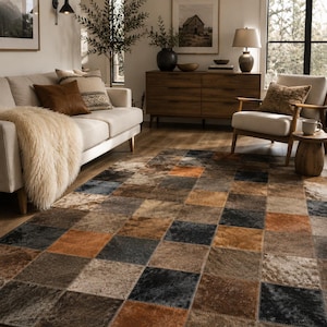 May include: A patchwork rug with a variety of colors including brown, black, and orange. The rug is made of squares of different textures and shades, creating a rustic and inviting look. The rug is placed in a living room setting.