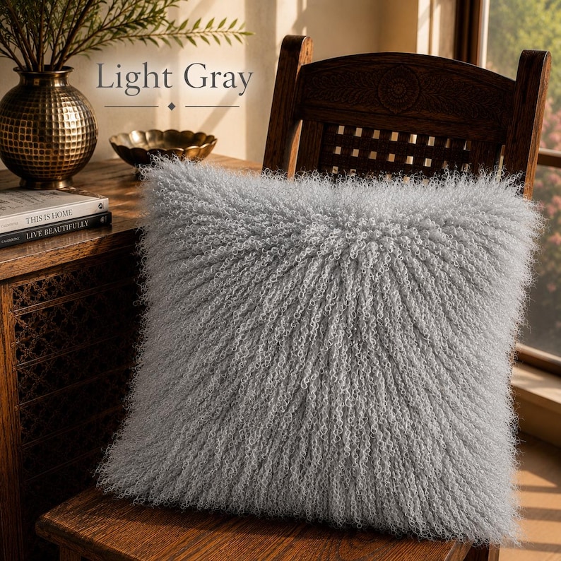 May include: A square throw pillow in a light gray color featuring a long, curly, shaggy texture across the entire surface. The pillow is positioned on a wooden chair. The text Light Gray is visible in the upper portion of the image.