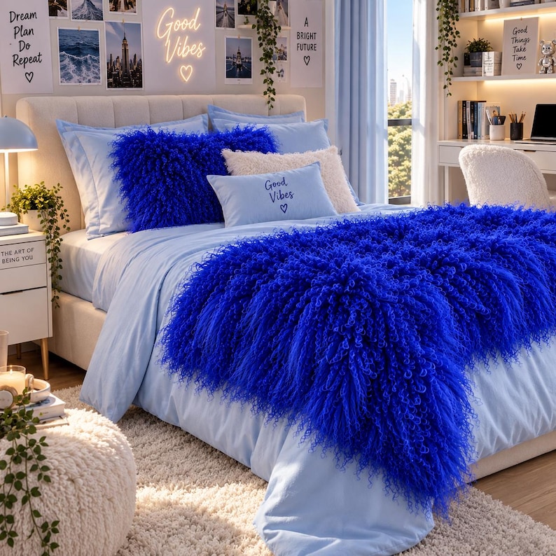 May include: A bed set featuring light blue sheets and a matching pillowcase with the text Good Vibes. The bed includes a large, vibrant royal blue shaggy faux fur throw blanket and a matching royal blue shaggy rectangular throw pillow.