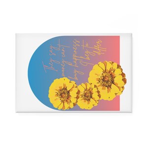 May include: A rectangular white magnet featuring three yellow flowers with brown centres. The magnet has a blue and pink gradient background with the text "They say money can't buy happiness, I beg to differ."