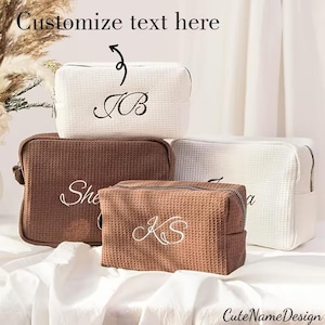 May include: Four waffle-textured cosmetic bags in white and brown, each with a zip closure and embroidered initials or a name. The bags are arranged on a white surface, with the text "Customize text here" and "CuteNameDesign" visible.