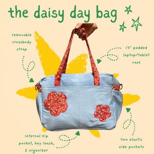 May include: A light blue fabric bag titled the daisy day bag, featuring red floral patterned straps and two matching floral flower appliqués. It includes a removable crossbody strap, a 33 cm padded laptop or tablet case, two elastic side pockets, an internal zip pocket, a key leash, and an organiser.