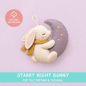 Puede incluir: Un adorno de fieltro con un conejo color crema de orejas rosadas y bufanda mostaza, abrazando una luna creciente morada decorada con tres pequeñas estrellas doradas bordadas. Incluye un lazo para colgar y el texto: INSTANT DOWNLOAD.