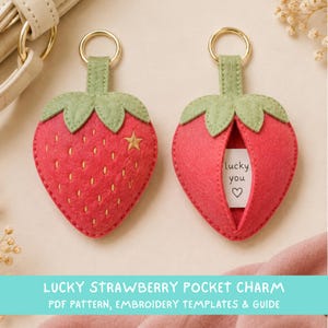 May include: Two strawberry-shaped felt keychains with green leaves and gold metal rings. One strawberry features yellow embroidered seeds and a small star, while the other has an opening revealing a white paper insert with the text lucky you and a heart.