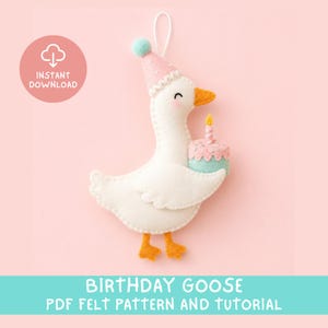 Op de afbeelding: Een witte viltgans ornament met een roze feesthoedje met een blauwe pompon, die een kleine blauwe en roze verjaardagstaart met een brandende kaars vasthoudt. De tekst INSTANT DOWNLOAD in een roze cirkel en BIRTHDAY GOOSE PDF FELT PATTERN AND TUTORIAL zijn zichtbaar.