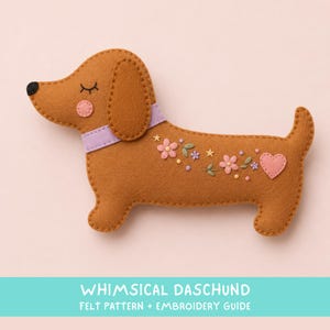 May include: A brown felt dachshund dog with a lavender collar, pink cheek, and closed eyes. The body features embroidered pink flowers, green leaves, small yellow stars, and a pink heart. Text at the bottom reads WHIMSICAL DASCHUND FELT PATTERN + EMBROIDERY GUIDE.