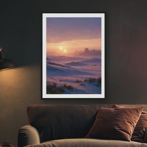 May include: A framed vertical wall art print depicting a surreal desert landscape covered in snow under a sunset sky with two suns visible on the horizon. The scene features rolling dunes, distant rock formations, and soft purple and orange hues.