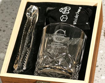 May include: A wooden gift box containing a crystal whiskey glass, ice tongs, and a black bag with the text "Whisky Swes". The glass is engraved with a letter and the name "Christian" and "Groomsman May 2026".