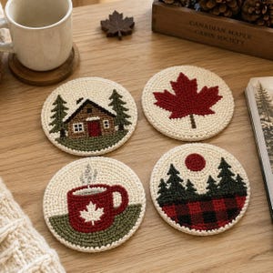 Puede incluir: Cuatro posavasos redondos de ganchillo con diseños inspirados en la naturaleza: una cabaña con pinos, una hoja de arce roja, una taza humeante con un emblema de hoja de arce y un bosque con un sol rojo sobre un patrón de cuadros rojo y negro.