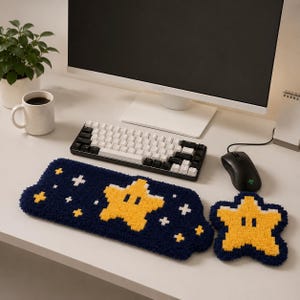 May include: A navy blue and yellow star-shaped desk mat and coaster set. The mat features a large yellow star and white crosses on a navy blue background. The coaster has a matching star design. A keyboard, mouse, and monitor are in the background.