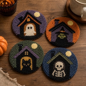 May include: Four round punch needle coasters featuring Halloween designs. One shows a ghost in a purple house, one a witch in an orange house, one a black cat in a green house, and one a skeleton in a blue house, all with yellow moons.