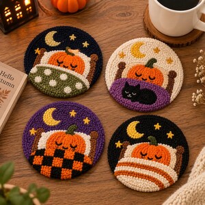 Puede incluir: Cuatro posavasos redondos de punch needle con una calabaza naranja durmiendo en una cama bajo una luna creciente amarilla y estrellas. Cada posavasos muestra un patrón de manta diferente, incluyendo lunares verdes, morado, cuadros negros y rayas.