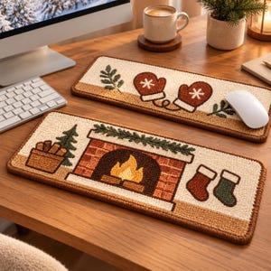 May include: Two rectangular keyboard wrist rests featuring textured, punch-needle style embroidery. One displays brown mittens and greenery on a cream background. The other depicts a brick fireplace with a fire, a pine tree, and two stockings.