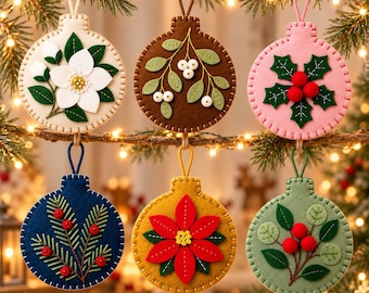 Op de afbeelding: Zes ronde vilten ornamenten met geborduurde botanische ontwerpen. De ornamenten tonen een witte magnolia, witte bessen op bruin, hulstbladeren met rode bessen op roze, dennennaalden op marineblauw, een rode kerstster en groene bladeren met rode bessen.