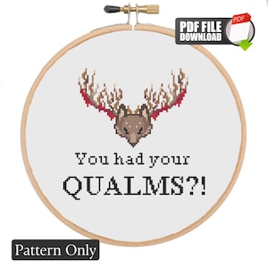 May include: A cross stitch pattern featuring a pixelated brown fox head with large, branching antlers in shades of brown and red. Below the fox, the text reads "You had your QUALMS?!". The design is displayed within a circular wooden embroidery hoop.