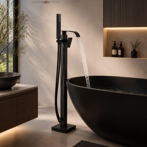Puede incluir: Un grifo de bañera negro mate montado en el suelo con base cuadrada, columna vertical alta, caño curvo y ducha de mano. El agua fluye desde el caño hacia una bañera negra grande de forma ovalada. El texto RoseByBerry es visible.