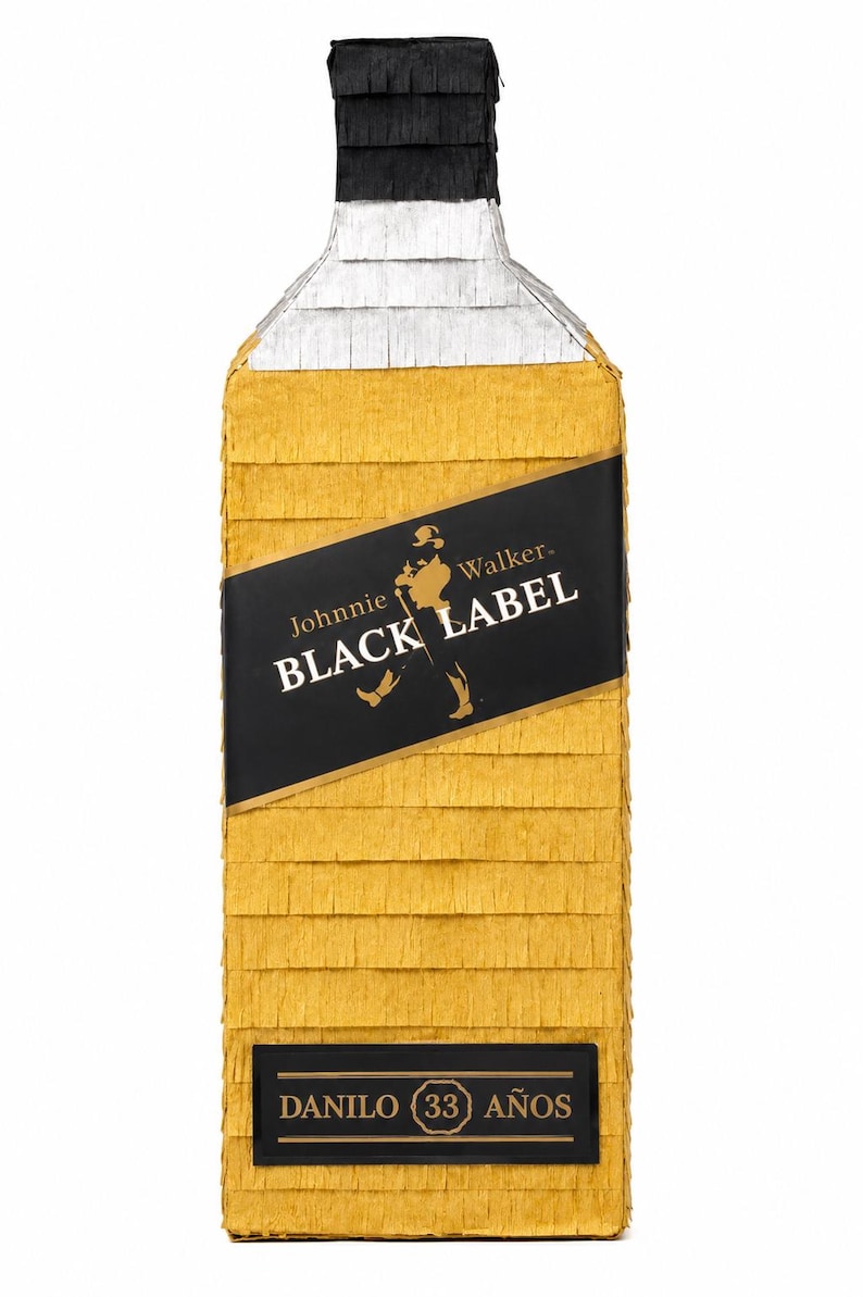 May include: A large, rectangular pi&ntilde;ata shaped like a Johnnie Walker Black Label bottle. The pi&ntilde;ata is primarily gold with a black label featuring the brand's logo and text. The top is black and white, and the bottom has text that reads "DANILO (33 A&Ntilde;OS".