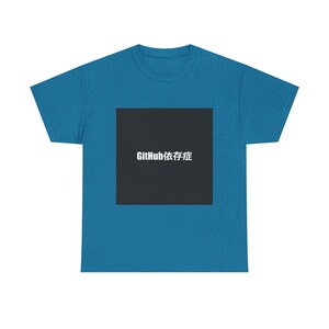 May include: Teal-colored t-shirt with a black square graphic. The graphic features white text that reads "GitHub Dependency Syndrome". The shirt is made of a soft material and has a classic crew neck.
