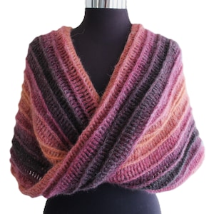 May include: A knitted shawl with a V-neck and a striped pattern in shades of pink, orange, and gray.