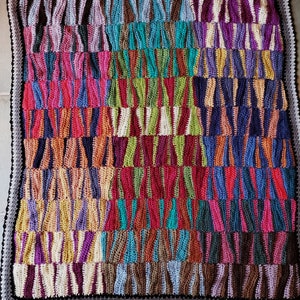 May include: A colorful crocheted blanket with a variety of different colored stripes and patterns. The blanket is made up of squares that are sewn together.