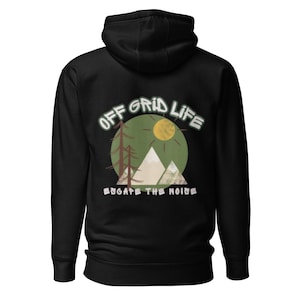 Op de afbeelding: Zwarte hoodie met een afbeelding op de achterkant. De afbeelding toont de tekst "OFF GRID LIFE" in witte en groene letters, met een groene cirkel, een gele zon, bergen en bomen. De tekst "ESCAPE THE NOISE" staat eronder.