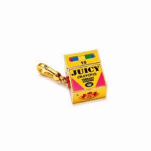 May include: A gold-tone metal charm shaped like a box of crayons. The box is yellow with pink triangular accents, featuring the text JUICY CRAYONS VIBRANT COLORS and the number 10. It includes a small lobster clasp for attachment to a bracelet or chain.