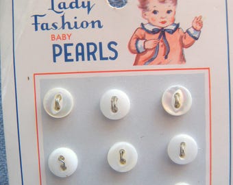 12 botones pequeños (7 mm) de nácar blanco, iridiscentes, con centro ojo de pez y 2 agujeros.