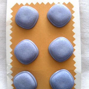 May include: Six light blue, square-shaped buttons on a vintage card. The buttons have a textured surface and are set against a gold-colored background. The card reads "Fashion-Tone SPECIAL VALUE BUTTONS" and "MADE IN U.S.A."