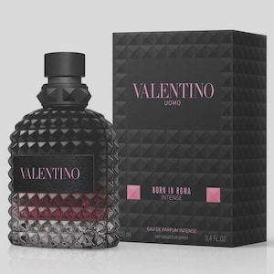 May include: Black Valentino Uomo Born in Roma Intense Eau de Parfum bottle and box. The bottle is a dark, textured design with a black cap and a section of red and silver. The box is black with pink text.