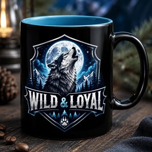 Può includere: Tazza in ceramica nera con interno blu, raffigurante un lupo che ulula davanti a una luna piena e a un paesaggio montuoso. Il testo "WILD & LOYAL" è visualizzato sotto. È inclusa anche un'impronta di zampa.