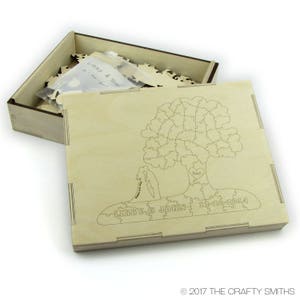May include: A wooden box with a lid open, revealing a wooden puzzle inside. The puzzle is shaped like a tree with a heart at the base. The text "Libby & John 12-20-2014" is engraved on the puzzle.