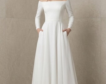 Vestido de noiva moderno, modelo A-line com ombros à mostra e mangas compridas.