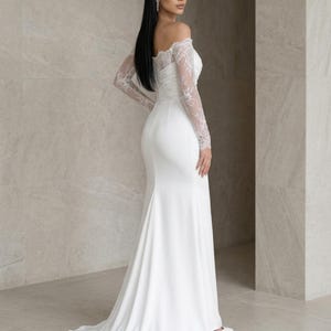 Puede incluir: Un vestido blanco largo hasta el suelo con escote de hombros descubiertos y mangas largas de encaje transparente. El corpiño es ajustado y se transforma en una falda lisa y fluida con una cola que se extiende por el suelo, en tela blanca.