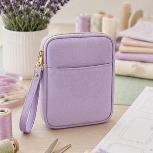 May include: A rectangular lavender fabric pouch featuring a gold-toned zipper closure and a matching wrist strap. The pouch has a simple, structured design with a front slip pocket and a smooth, solid-colored exterior finish.