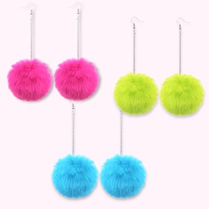 May include: Three pairs of dangle earrings featuring fluffy, spherical pom-poms in bright neon pink, lime green, and electric blue. Each earring consists of a silver-toned metal chain attached to a fishhook ear wire and a soft, textured pom-pom.