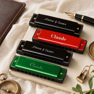 Puede incluir: Cuatro armónicas con cubiertas metálicas en negro, rojo, negro y verde. Las armónicas negras están grabadas con el texto Ninive & Cesar, mientras que las armónicas roja y verde tienen grabado el nombre Claude en una fuente cursiva blanca.