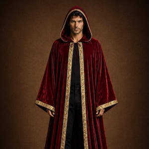 May include: A long, hooded burgundy velvet cloak with gold trim. The cloak is open in the front, revealing black clothing underneath. The hood and sleeves are also trimmed with gold. The cloak is floor-length.