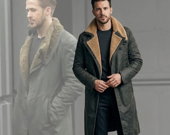 Puede incluir: Un abrigo largo de color verde oscuro con cuello de borrego beige. El abrigo está abotonado y se lleva sobre un jersey gris oscuro y pantalones negros. El abrigo parece estar hecho de un material duradero, y el estilo general es clásico y atemporal.