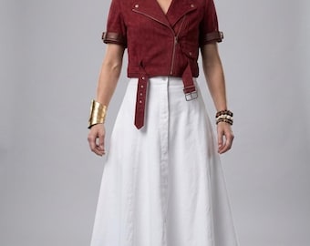 Puede incluir: Una chaqueta motera de manga corta en ante rojo oscuro con cuello marrón, cremallera asimétrica y cinturón con hebilla, combinada con una falda blanca de corte en A hasta los pies y botas de combate marrones con puños doblados.